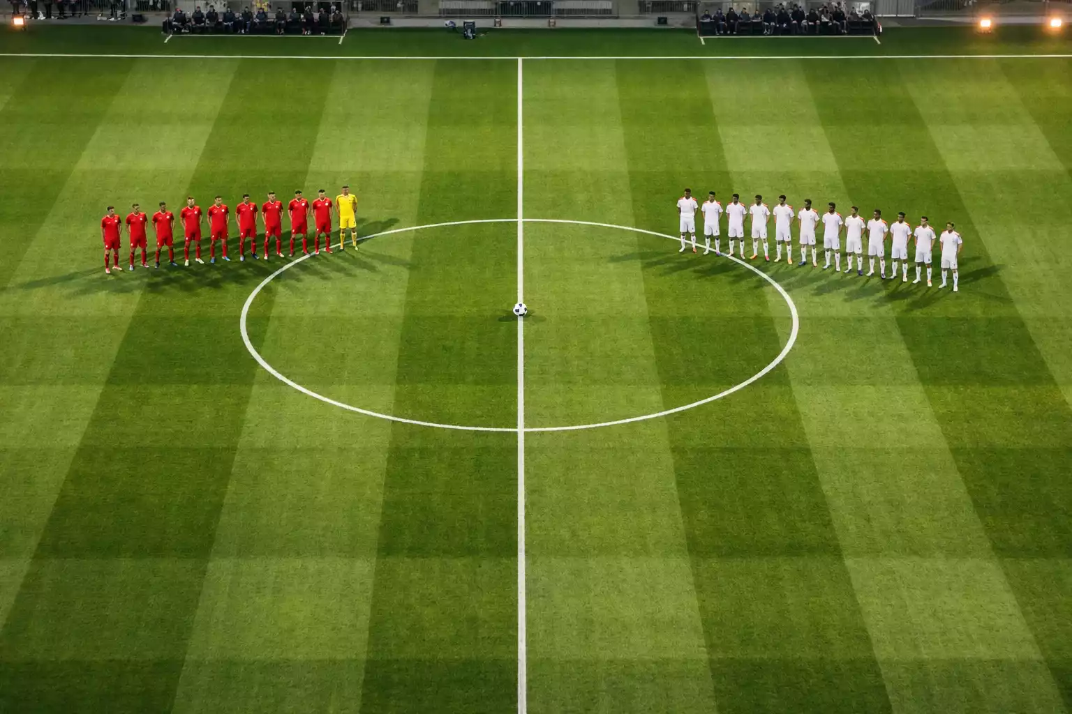 Campo da calcio visto dall'alto con due squadre schierate prima del fischio d'inizio